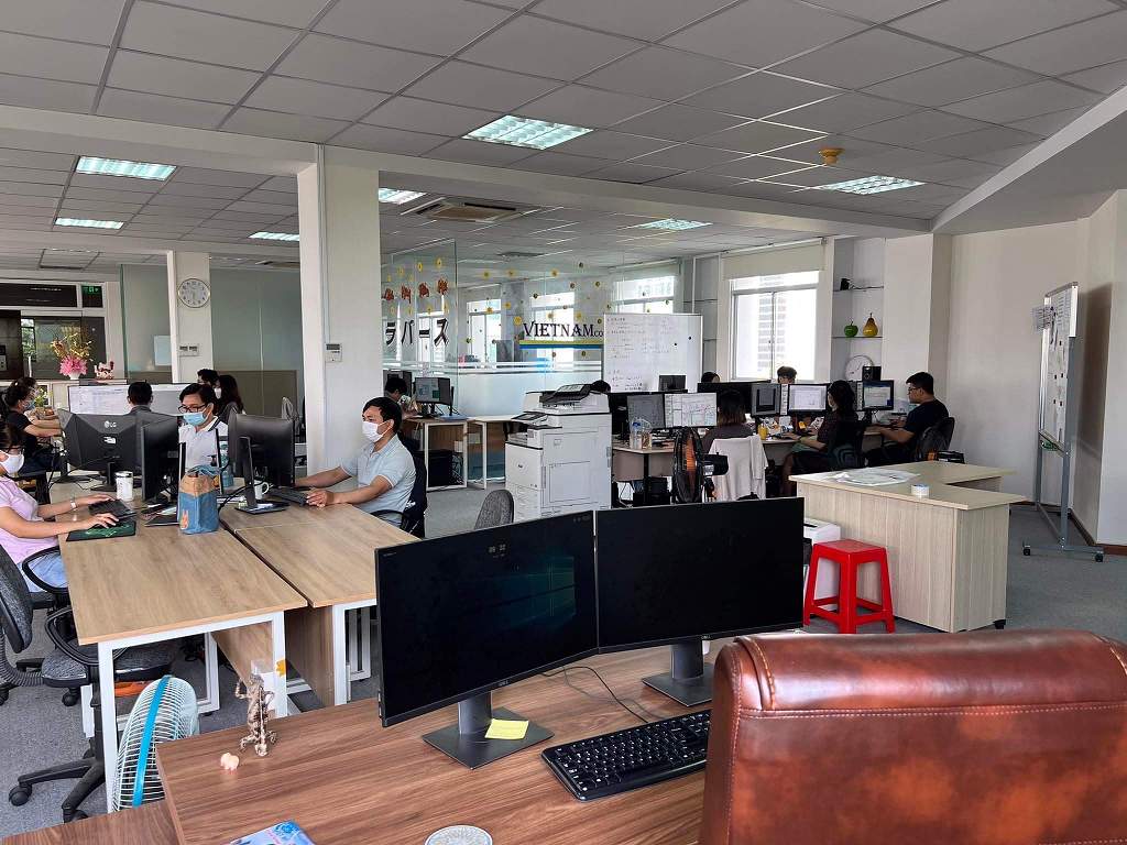 Open-plan office of Travers Vietnam with the Travers Vietnam sign on the glass wall